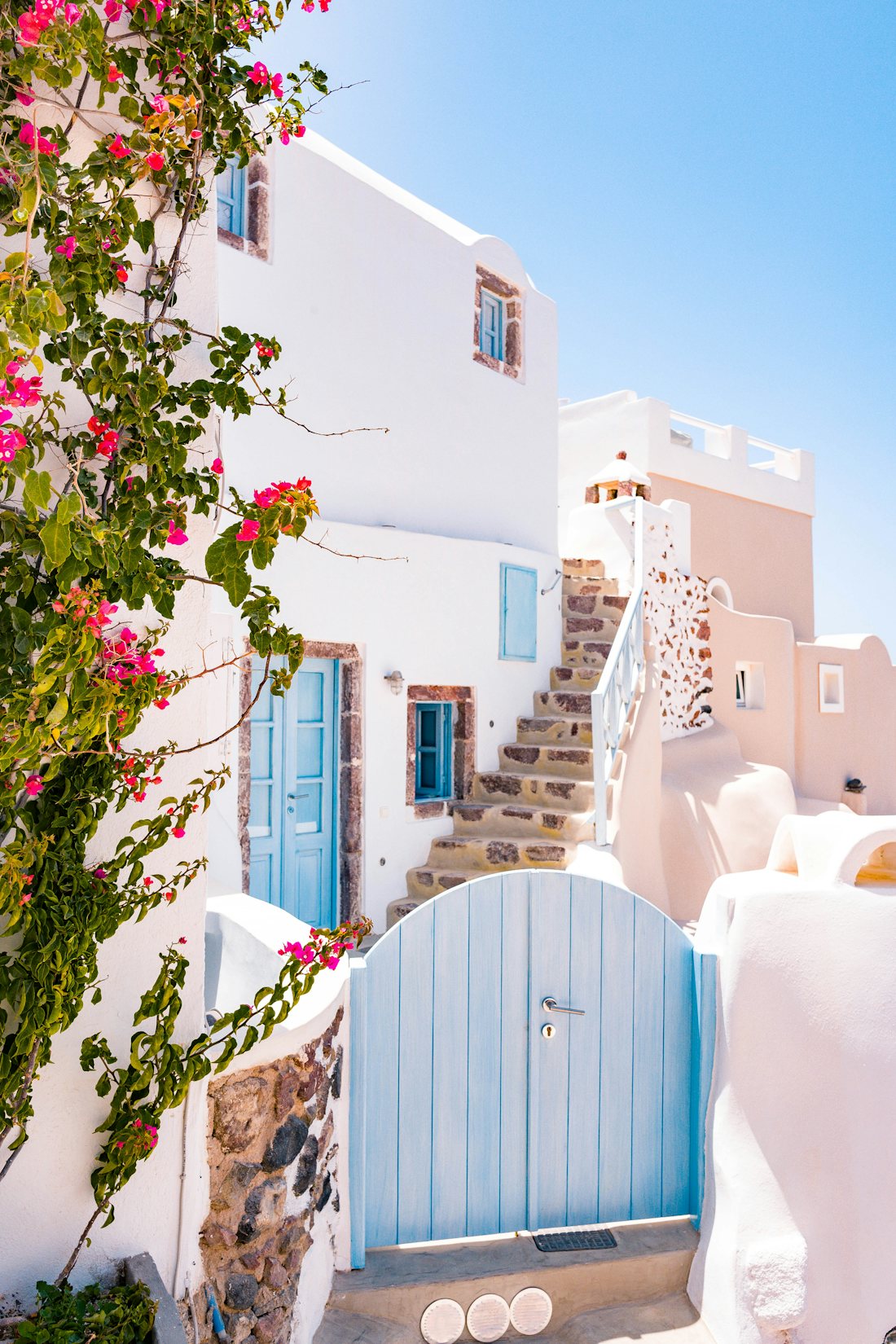 Whitewashed island house with blue doors and bougainvillea