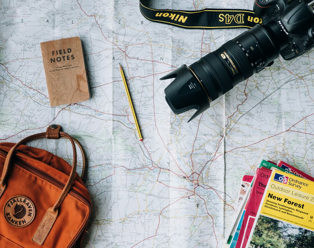 Map, notebook and camera laid out for trip planning