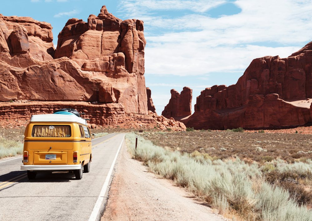 Vintage camper van on a desert road among red rocks